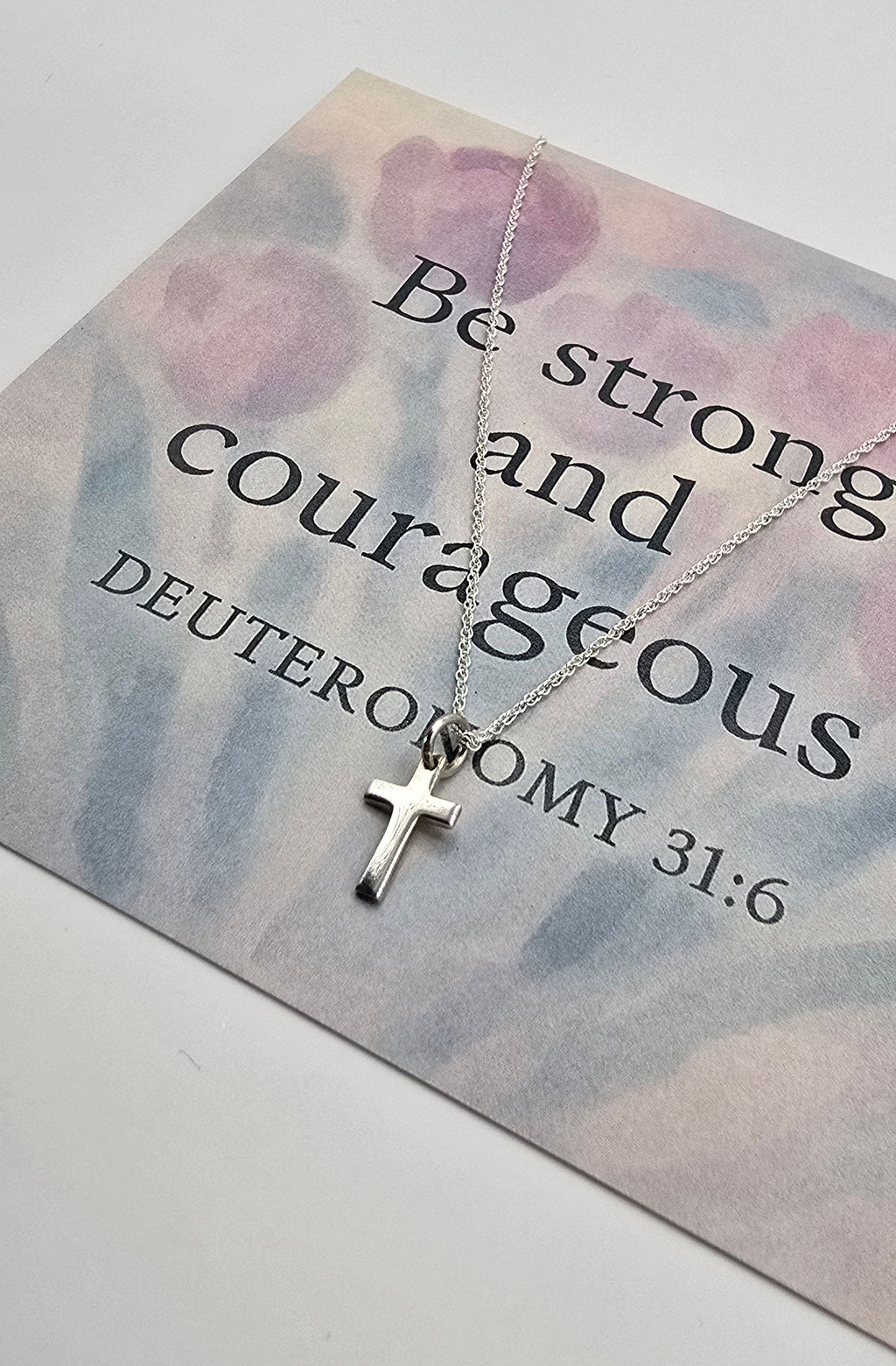 Silver cross necklace on a card with Br strong and courageous 