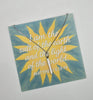 Necklace with a pendant on a card featuring a sun design and text.