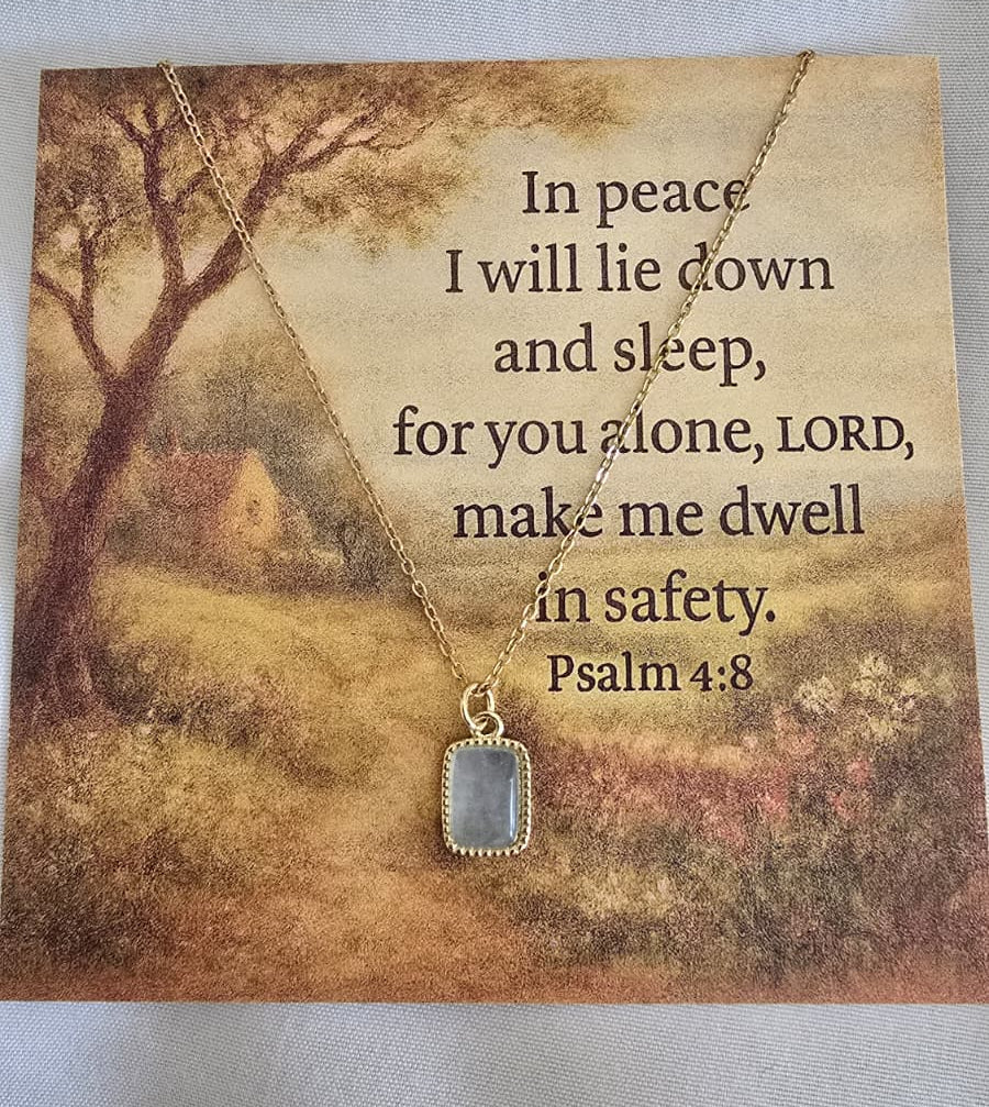 Necklace with pendant on a card featuring a scenic landscape and Psalm 4:8 text.
