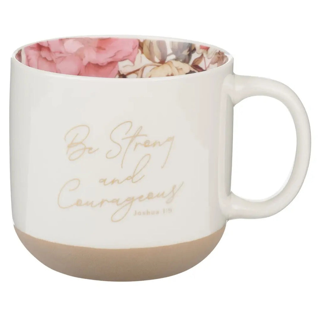 White mug with floral interior, gold text 'Be Strong and Courageous', and beige base on a white background